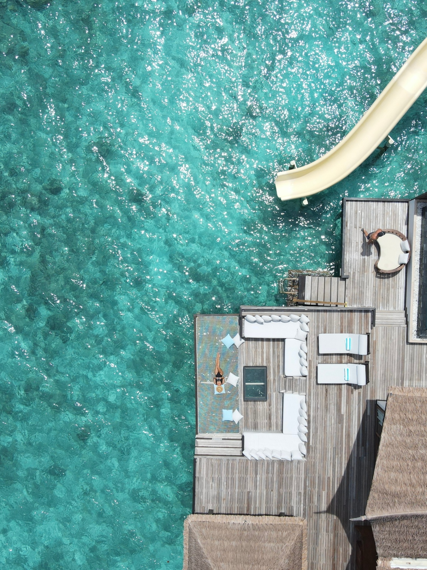 Aerial view of an overwater villa deck on a turquoise lagoon